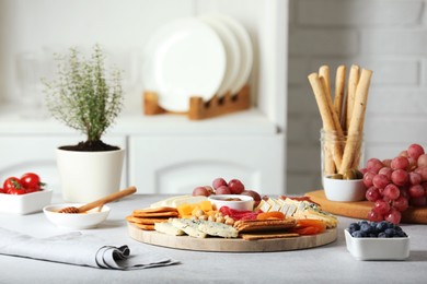 Photo of Different types of cut cheese and other snacks on light textured table indoors