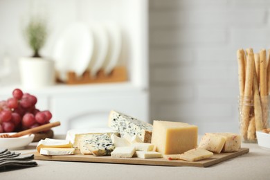 Photo of Different types of cut cheese and other snacks on light textured table indoors