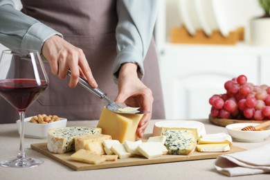 Photo of Woman slicing delicious cheese at light textured table indoors, closeup