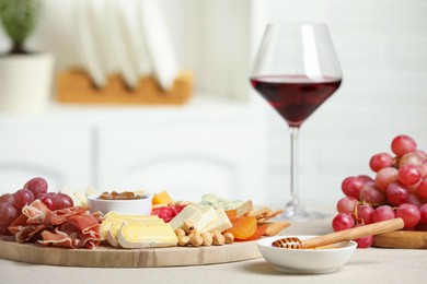 Photo of Different types of cut cheese and other snacks on light textured table, closeup