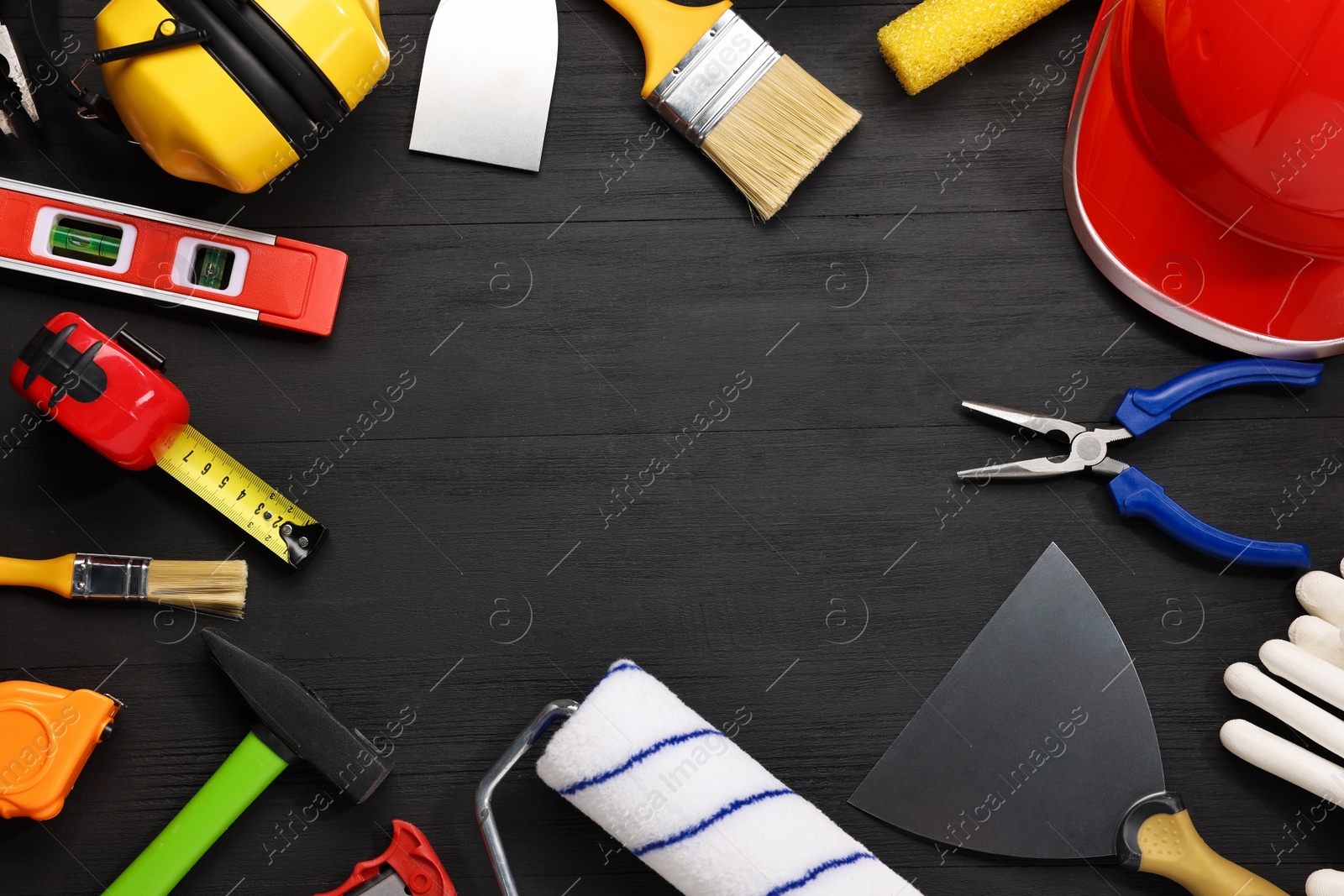 Photo of Frame made of different construction materials and tools on black wooden table, flat lay. Space for text