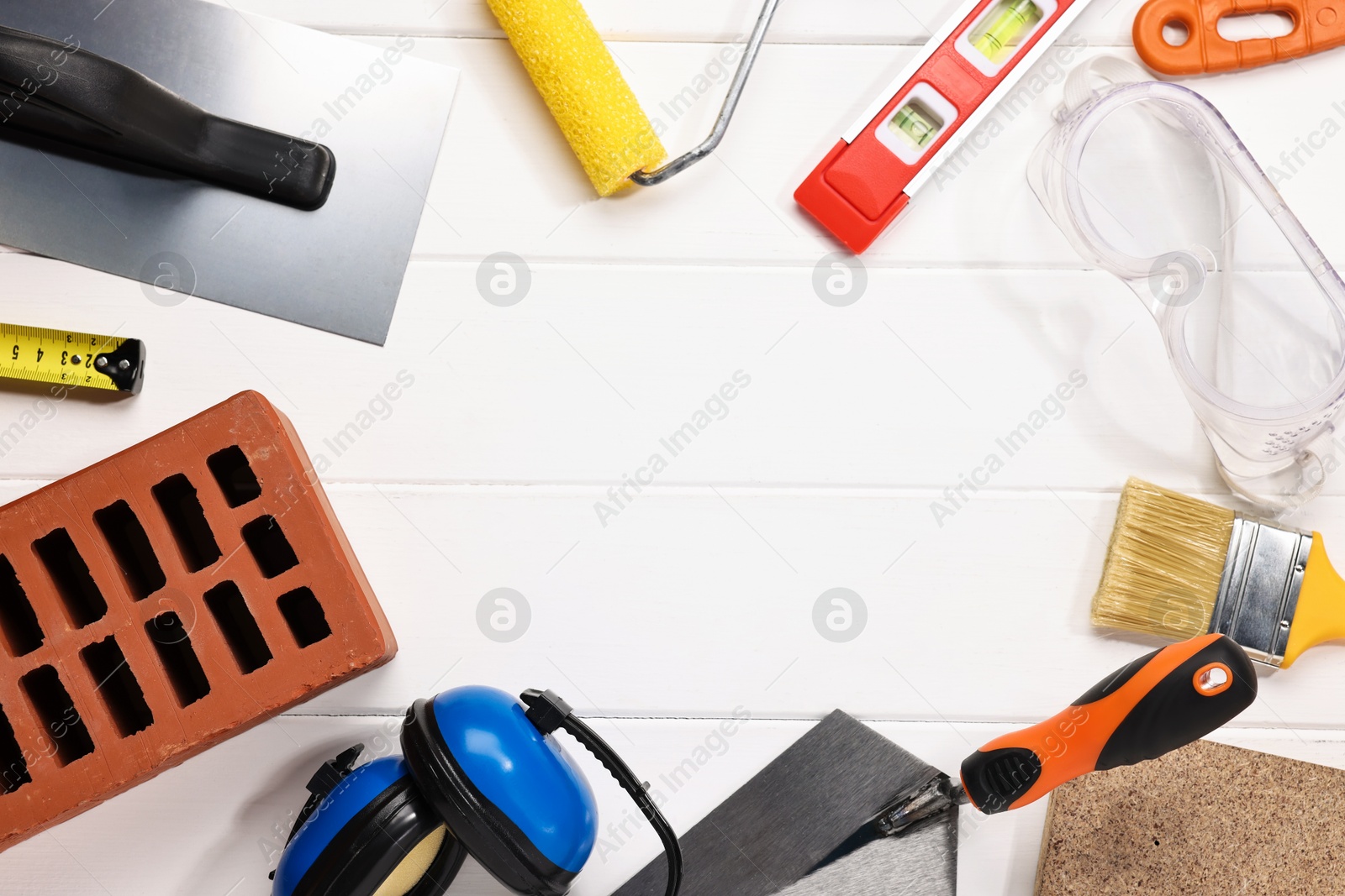 Photo of Frame made of different construction materials and tools on white wooden table, flat lay. Space for text