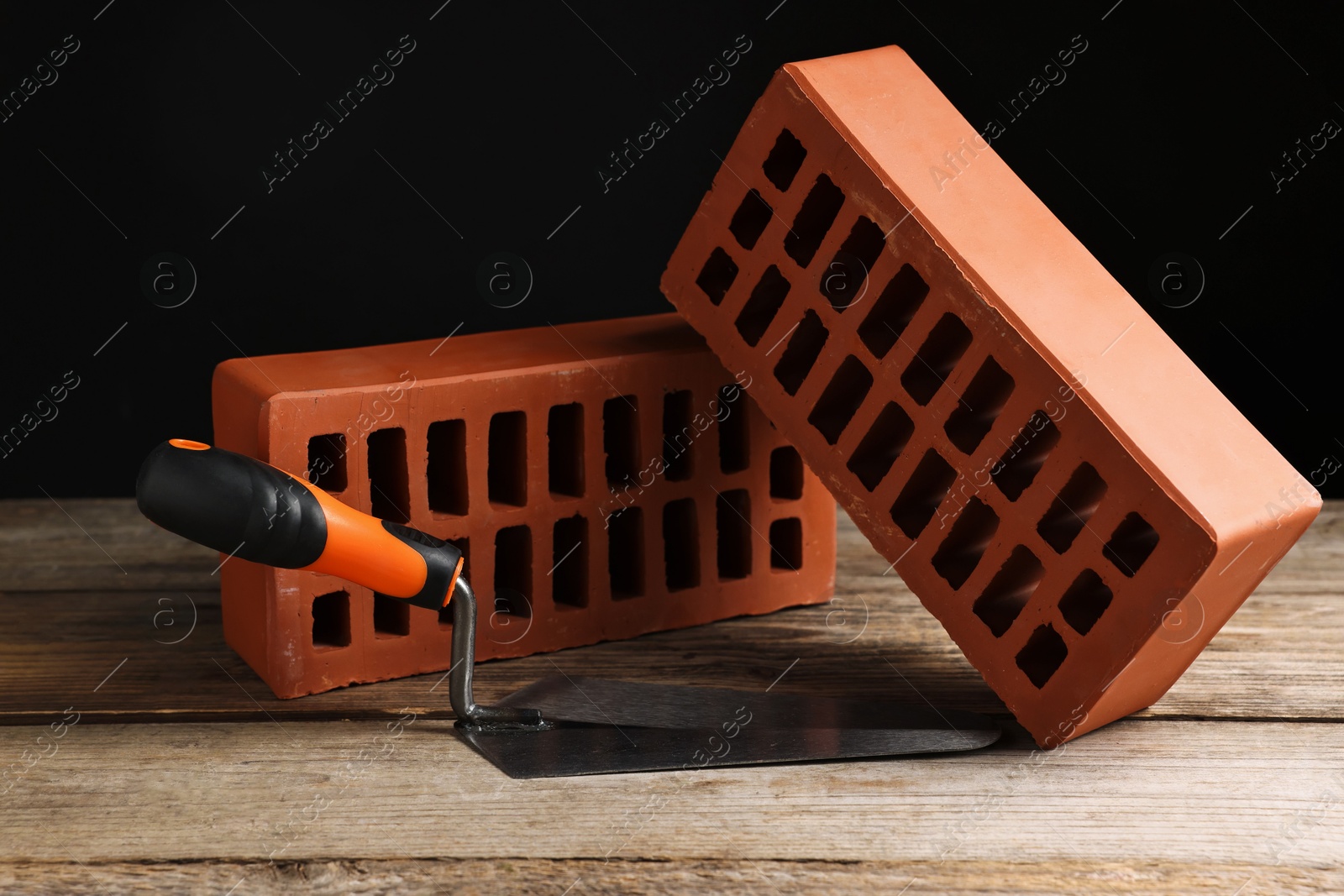 Photo of Bricks and bucket trowel on wooden table