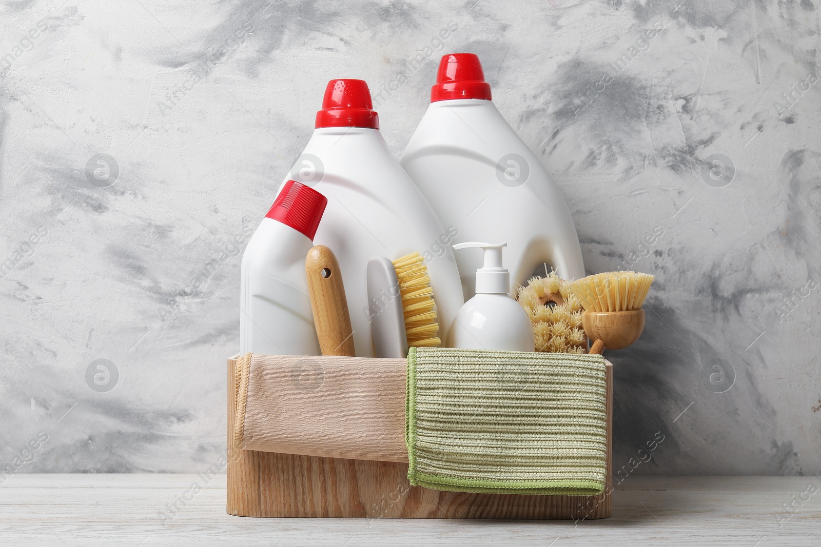 Photo of Eco-friendly cleaning products and supplies in crate on light wooden table