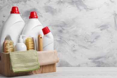 Photo of Eco-friendly cleaning products and supplies in crate on light wooden table, space for text