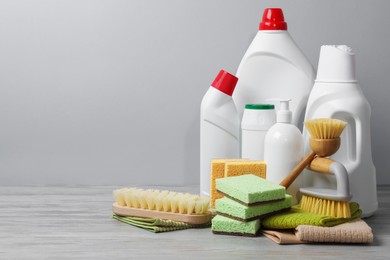 Photo of Eco-friendly cleaning products and supplies on wooden table against grey background, space for text