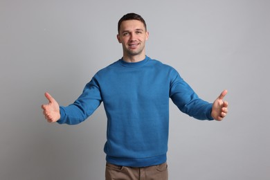 Photo of Cheerful man welcoming guests on light grey background