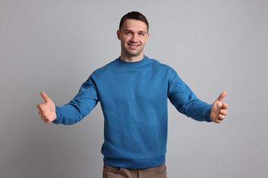 Photo of Cheerful man welcoming guests on light grey background