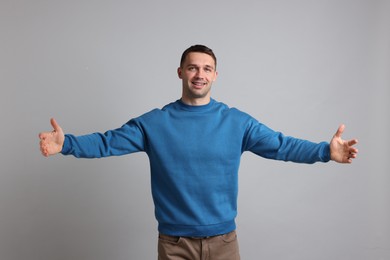 Photo of Cheerful man welcoming guests on light grey background