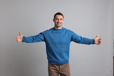 Photo of Cheerful man welcoming guests on light grey background