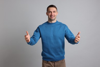 Photo of Cheerful man welcoming guests on light grey background