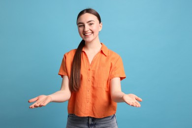 Photo of Cheerful woman welcoming guests on light blue background