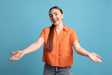 Photo of Cheerful woman welcoming guests on light blue background