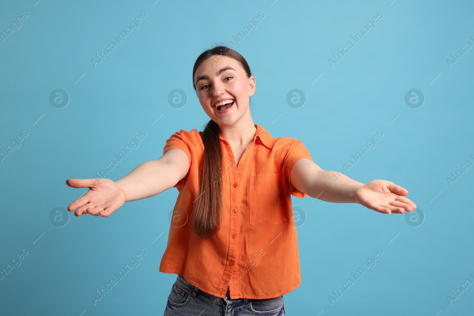 Photo of Cheerful woman welcoming guests on light blue background