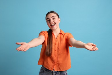 Photo of Cheerful woman welcoming guests on light blue background