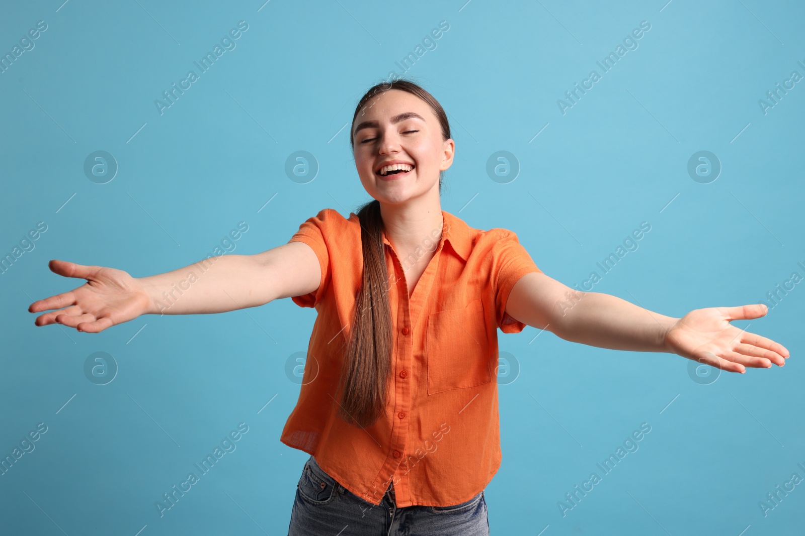 Photo of Cheerful woman welcoming guests on light blue background