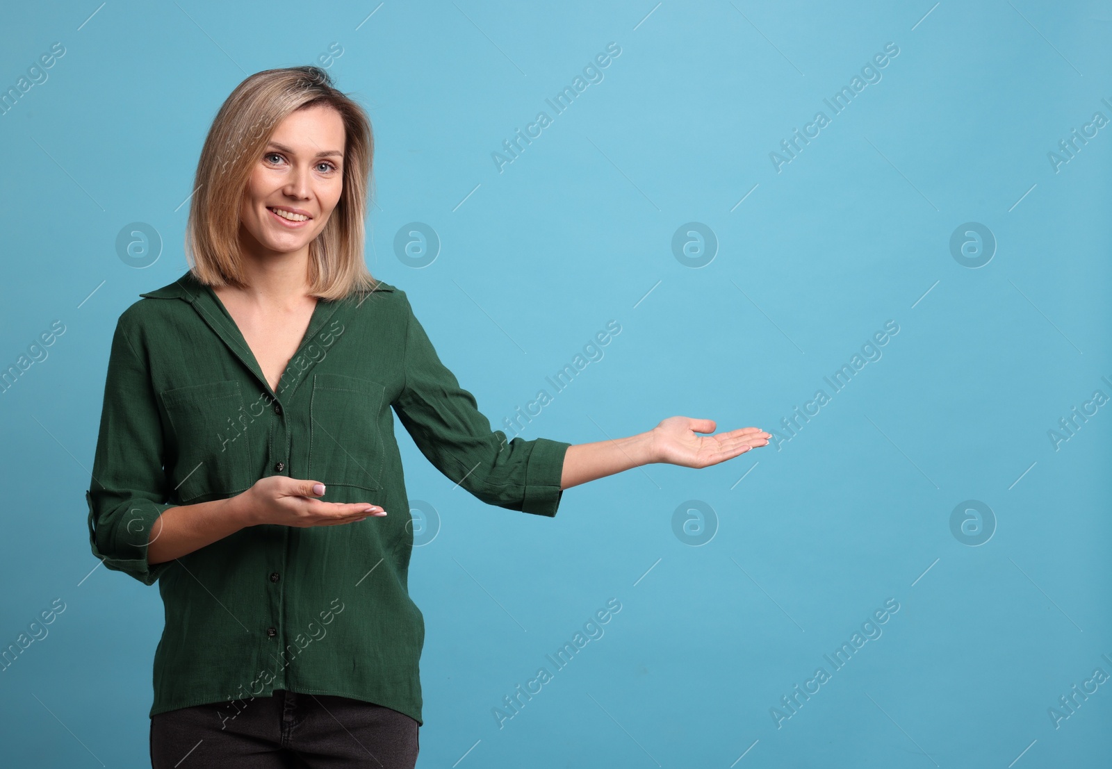 Photo of Cheerful woman welcoming guests on light blue background. Space for text