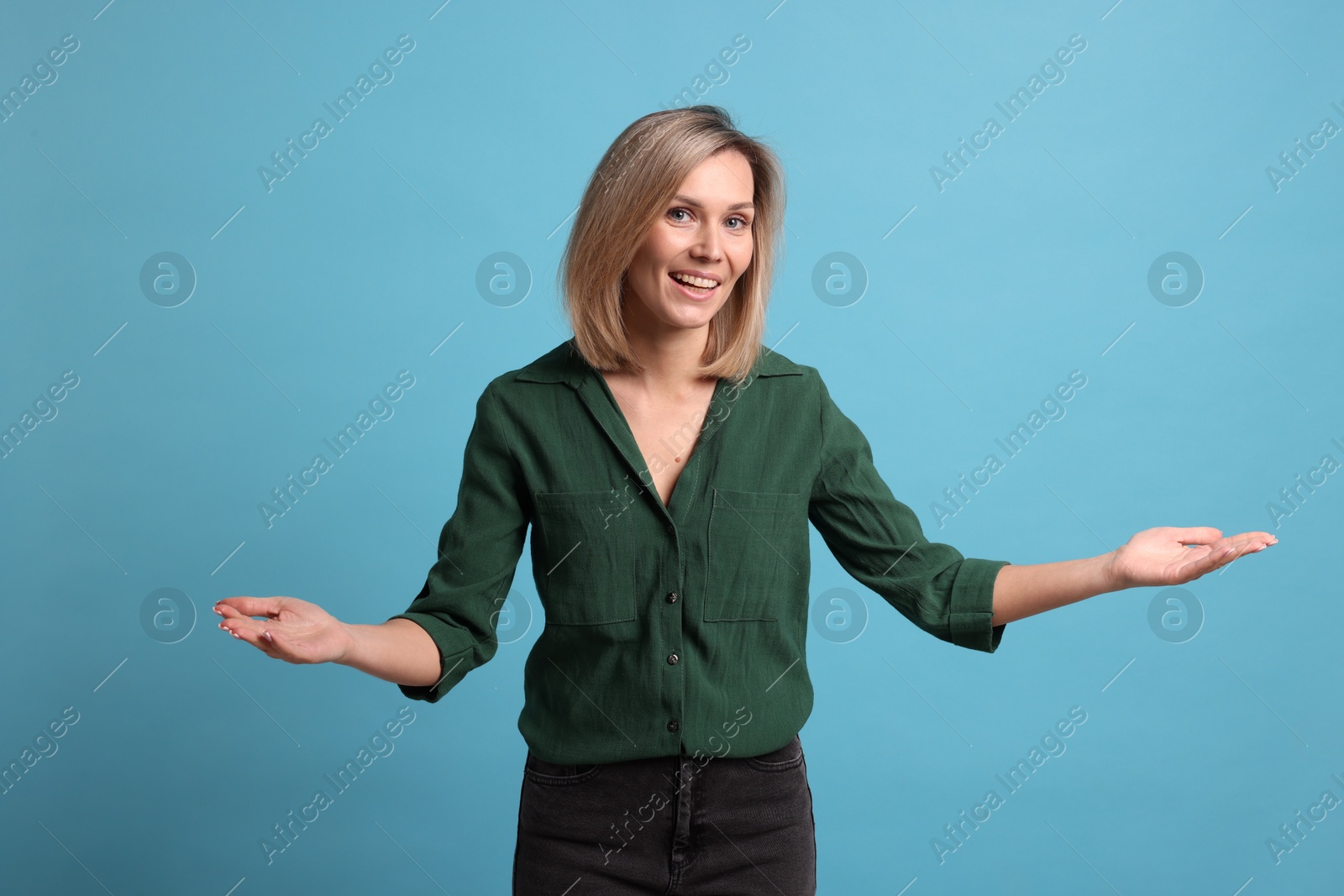 Photo of Cheerful woman welcoming guests on light blue background