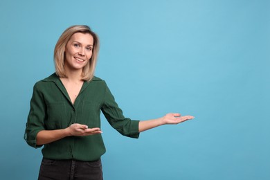 Photo of Cheerful woman welcoming guests on light blue background. Space for text