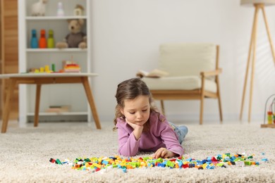 Photo of Cute girl playing with building blocks on floor at home