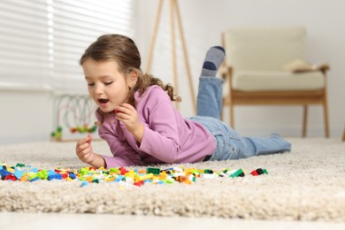 Photo of Cute girl playing with building blocks on floor at home