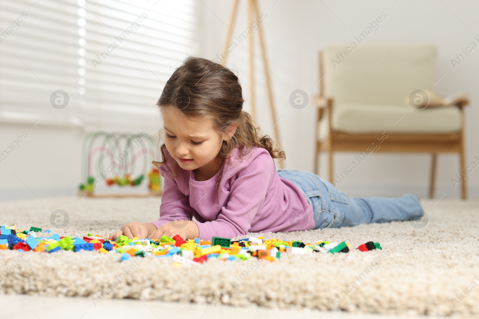 Photo of Cute girl playing with building blocks on floor at home