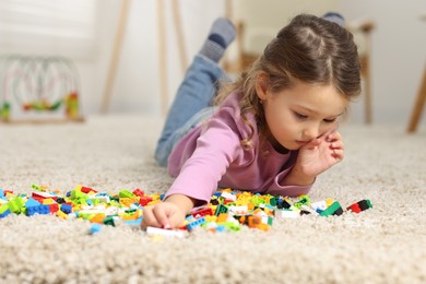 Photo of Cute girl playing with building blocks on floor at home