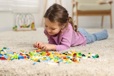 Photo of Cute girl playing with building blocks on floor at home