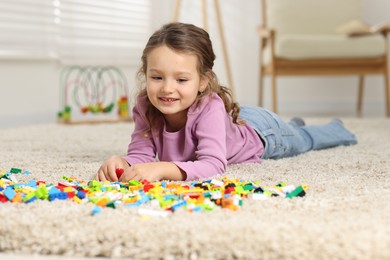 Photo of Cute girl playing with building blocks on floor at home