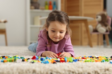 Photo of Cute girl playing with building blocks on floor at home