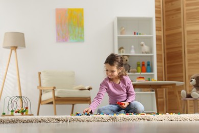 Photo of Cute girl playing with building blocks on floor at home. Space for text