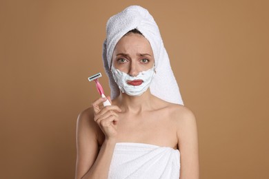 Photo of Beautiful woman with razor on brown background. Hair removal tool