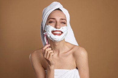 Photo of Happy woman shaving facial hair with razor on brown background