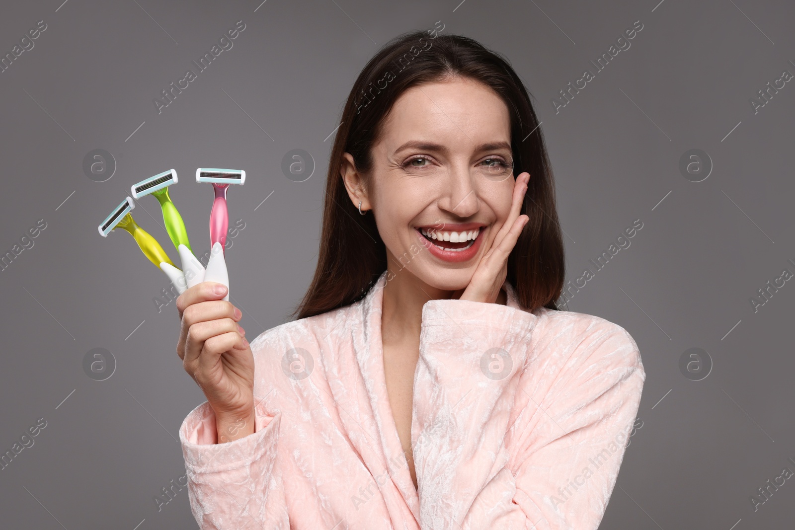 Photo of Happy woman with different razors on grey background. Hair removal tools