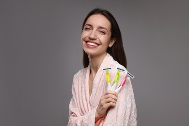 Photo of Happy woman with different razors on grey background. Hair removal tools