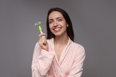 Photo of Happy woman with razor on grey background. Hair removal tool