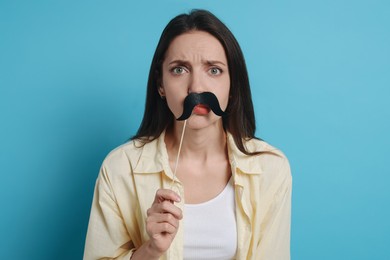 Photo of Woman with fake paper mustache on light blue background