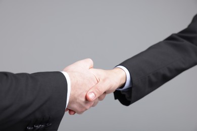 Photo of Businessmen shaking hands on grey background, closeup