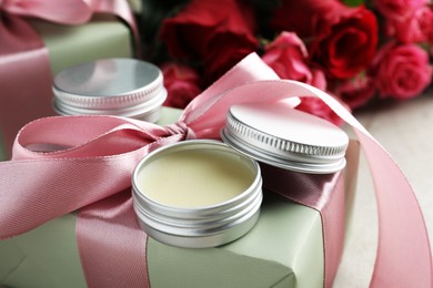 Photo of Natural solid perfume, gift box and flowers on light table, closeup