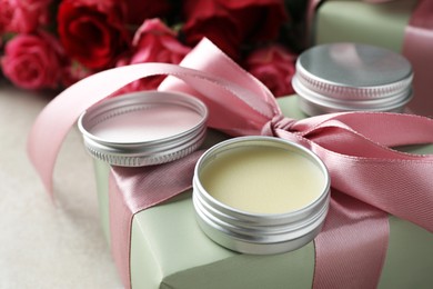 Photo of Natural solid perfume, gift box and flowers on light table, closeup