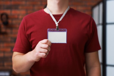 Photo of Man with blank badge in office, closeup