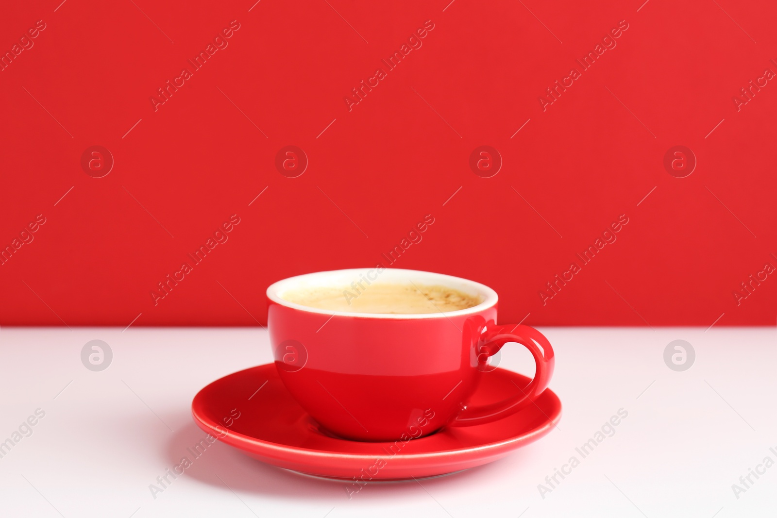 Red cup with coffee on white table Photo of Red cup with coffee on white table