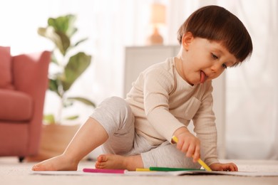 Photo of Cute little boy drawing on floor at home