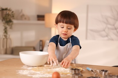 Photo of Cute little boy shaping dough with rolling pin at table indoors