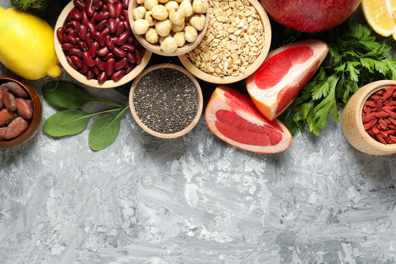 Photo of Different superfood products on grey table, flat lay. Space for text