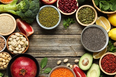 Photo of Frame of different superfood products on wooden table, flat lay. Space for text