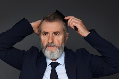 Photo of Handsome man combing his hair on dark grey background