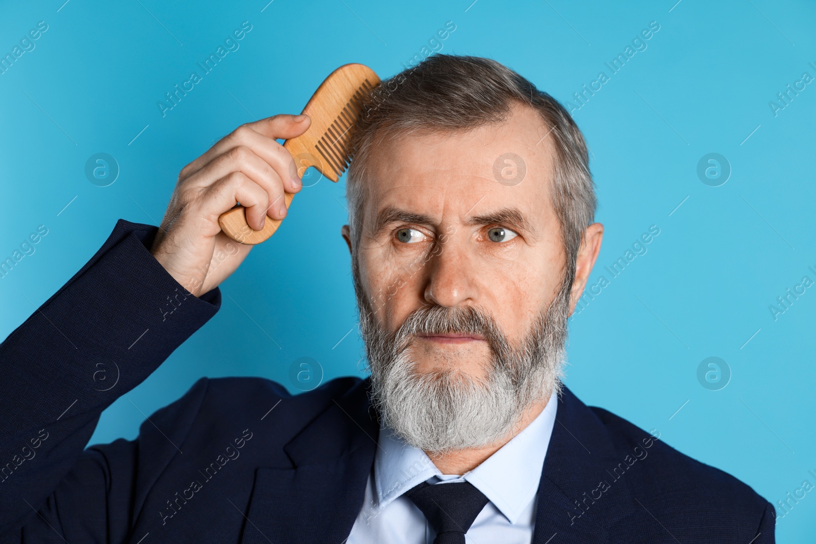 Photo of Handsome man combing his hair on light blue background