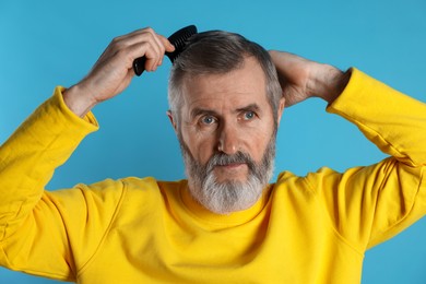 Photo of Handsome man combing his hair on light blue background