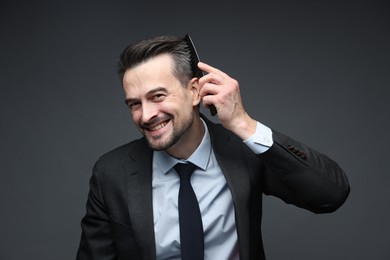 Photo of Handsome businessman combing his hair on dark background